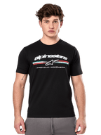 Alpinestars Prevail CSF Tee, maglietta nera a maniche corte indossata da un modello, con logo bianco, striscia tricolore e grafica "PREMIUM RACEWEAR", streetwear casual motorsport