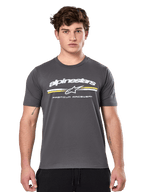 Alpinestars Prevail CSF Tee, maglietta a maniche corte grigio antracite, logo Alpinestars bianco con strisce gialle e bianche e grafica 'Premium Racewear', streetwear casual ispirato al motorsport