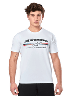 Alpinestars Prevail CSF Tee, t-shirt bianca a maniche corte, con logo frontale a strisce tricolore stile paddock con accenti rossi e blu, marchio Alpinestars nero e scritta 'Premium Racewear', indossata da un modello uomo, abbigliamento casual motorsport