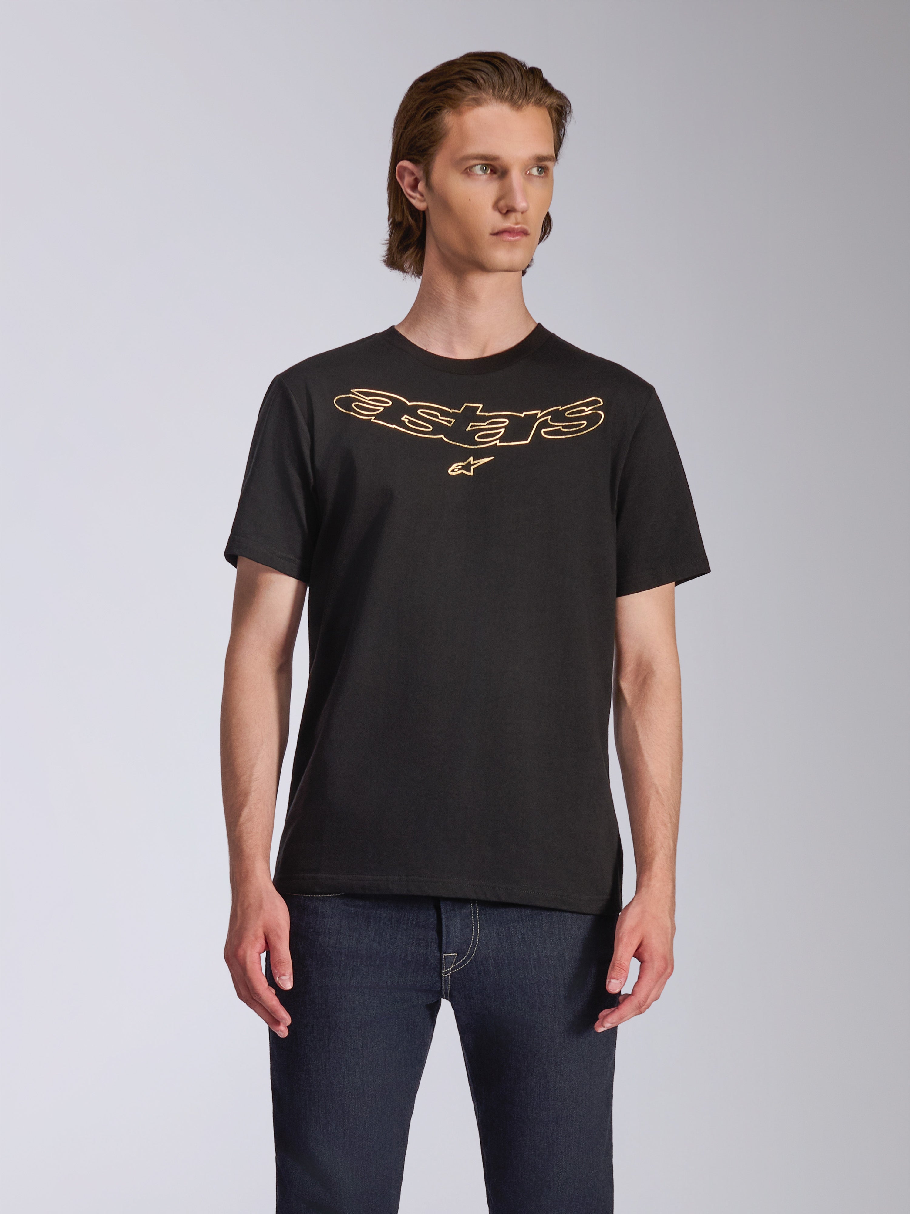 Alpinestars Luxo CSF Tee, t-shirt a maniche corte, nero, logo Astars con profilo dorato sul petto, indossata con jeans blu scuro, abbigliamento streetwear casual motorsport