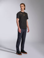T-shirt Alpinestars Luxo CSF, maglietta a maniche corte, nera, logo Astars dorato profilato sul petto, indossata da un modello con jeans denim scuro e sneakers nere, streetwear casual motorsport