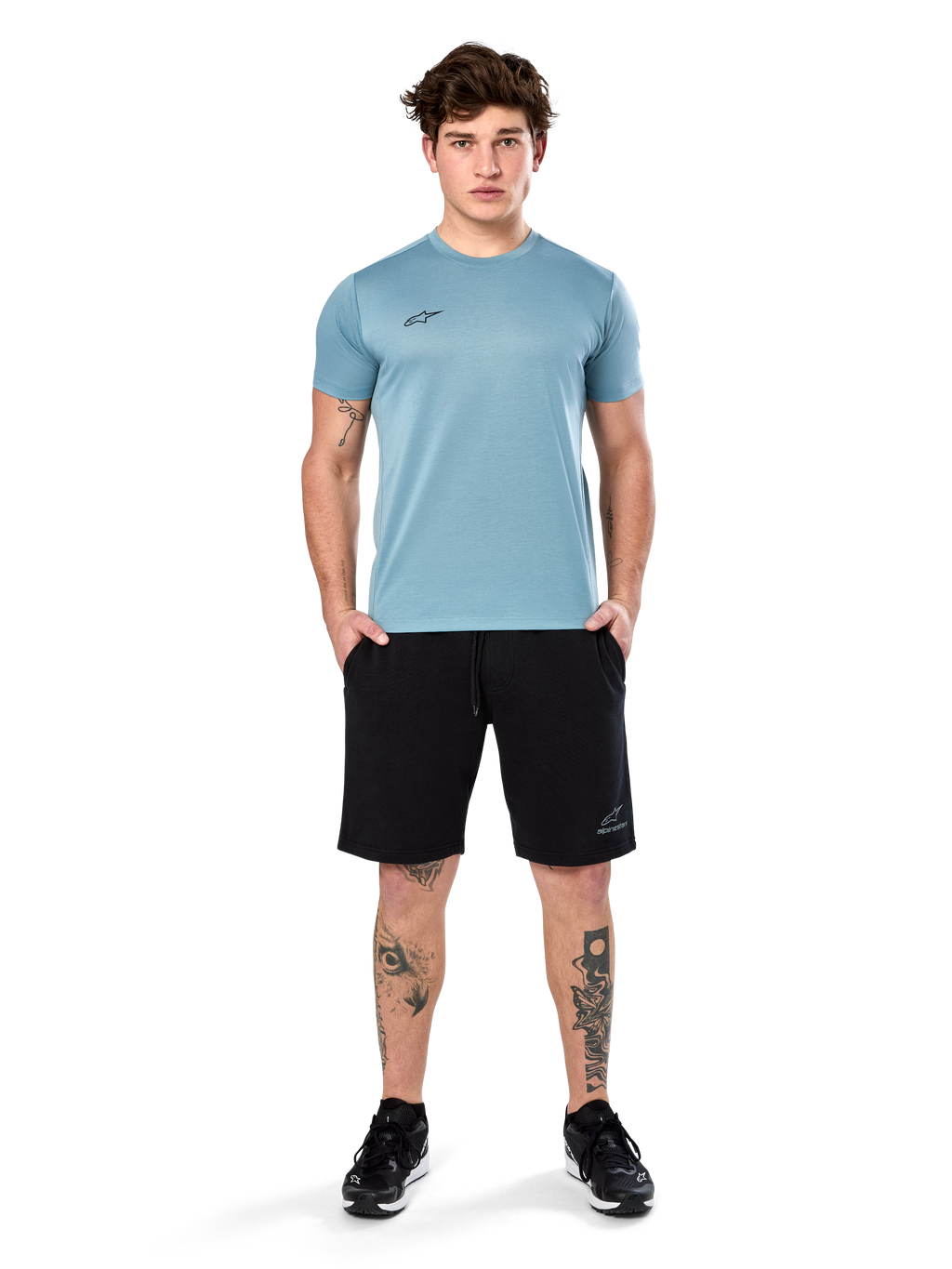 Alpinestars Point Performance Tee, t-shirt a maniche corte, blu ghiaccio, con un piccolo logo nero sul davanti, girocollo, indossata da un modello con pantaloncini neri e sneakers nere, abbigliamento sportivo casual traspirante