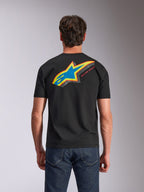 Alpinestars Angler CSF Tee, t-shirt a maniche corte, nero, vista posteriore con vivace logo Astars multicolore con riempimento traforato e scritta 'RACING AHEAD', indossata con jeans blu, abbigliamento casual ispirato al motorsport