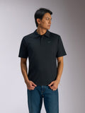 Polo Alpinestars Impetus Sport, polo a maniche corte nera, chiusura a tre bottoni e colletto dello stesso tessuto, piccolo logo Astars grigio sul petto a sinistra, indossata con jeans blu, abbigliamento sportivo casual ispirato al motorsport