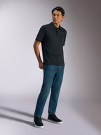 Polo Alpinestars Impetus Sport, polo a maniche corte, nera, caratterizzata da un discreto logo sul petto e abbottonatura a tre bottoni, indossata da un modello con jeans blu e sneaker nere, abbigliamento lifestyle casual ispirato al motorsport