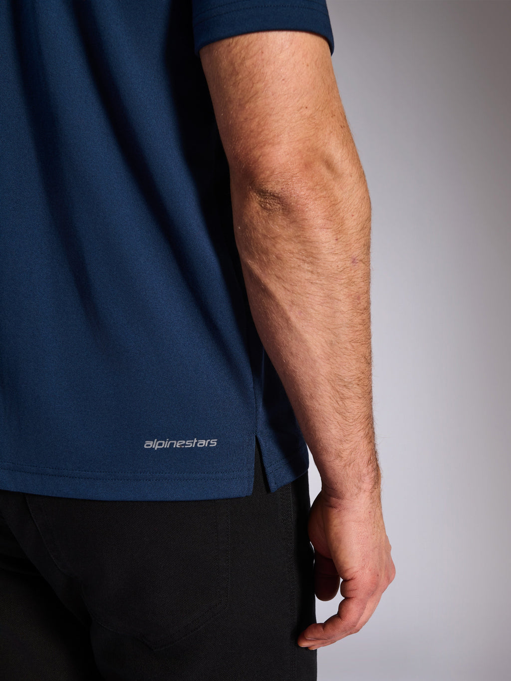 Alpinestars Impetus Sport Polo, Navy, primo piano dell'orlo inferiore con scritta Alpinestars e spacco laterale, trama in maglia a rete finta, abbigliamento sportivo casual da motorsport