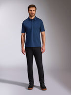 Alpinestars Impetus Sport Polo, polo a maniche corte, blu navy, piccolo logo Astars argento sul petto, abbottonatura a tre bottoni, indossata da un modello con pantaloni neri e stivali, abbigliamento sportivo casual ispirato al motorsport