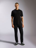Alpinestars Polo Endeavor Classic, polo in piqué a maniche corte, nero, piccolo logo Astars bianco sul petto, colletto e polsini a coste, indossata da un modello con pantaloni neri e sneakers, abbigliamento streetwear casual motorsport