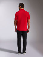 Polo Alpinestars Endeavor Classic, polo in piqué rossa, vista posteriore, indossata con pantaloni neri, streetwear casual per il motorsport con colletto e polsini a coste
