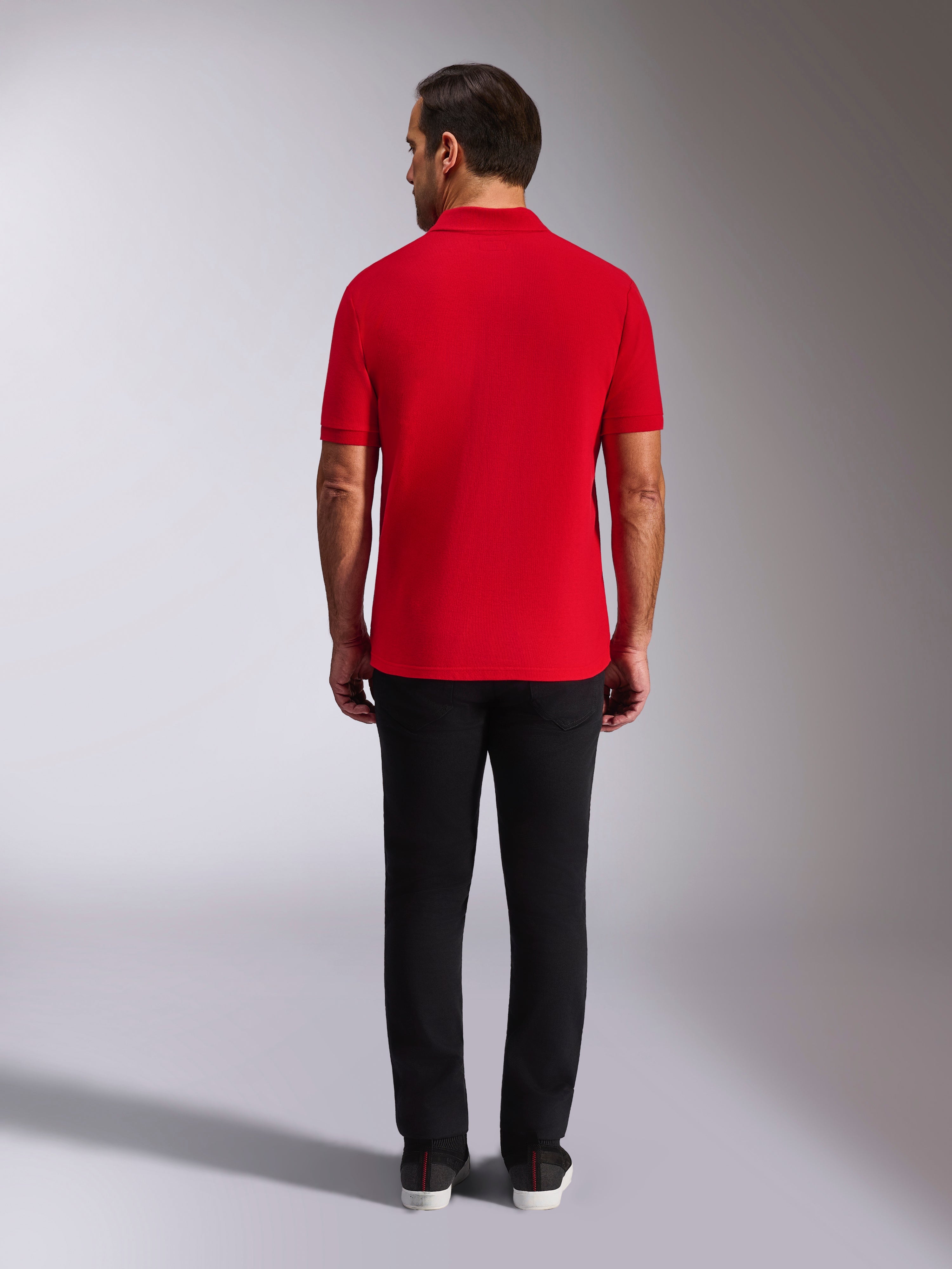 Polo Alpinestars Endeavor Classic, polo in piqué rossa, vista posteriore, indossata con pantaloni neri, streetwear casual per il motorsport con colletto e polsini a coste
