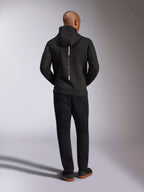 Alpinestars Insight Hoodie, nero, vista posteriore su modello, caratterizzata da un logo a striscia bianca verticale sul retro con scritta "Racing Ahead", felpa sportiva casual in pile double face tri-blend, abbinata a pantaloni neri.