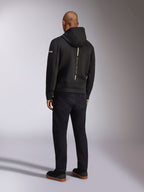 Alpinestars Insight Hoodie, felpa sportiva nera, vista posteriore con striscia bianca verticale e branding 'RACING AHEAD', logo sulla manica, abbinata a pantaloni neri e sneakers, design casual ispirato al motorsport