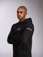 Alpinestars Insight Hoodie, felpa sportiva casual, nera, logo Astars bianco sul petto e logo Alpinestars Word sulla manica, modello che indossa la felpa con le braccia incrociate, pregiata costruzione in pile double face