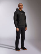 Alpinestars Insight Hoodie, nero, felpa casual pullover in pile con logo Astars bianco sul petto, tasca a marsupio, indossata con pantaloni neri e sneakers, scatto in studio a figura intera, streetwear ispirato al motorsport