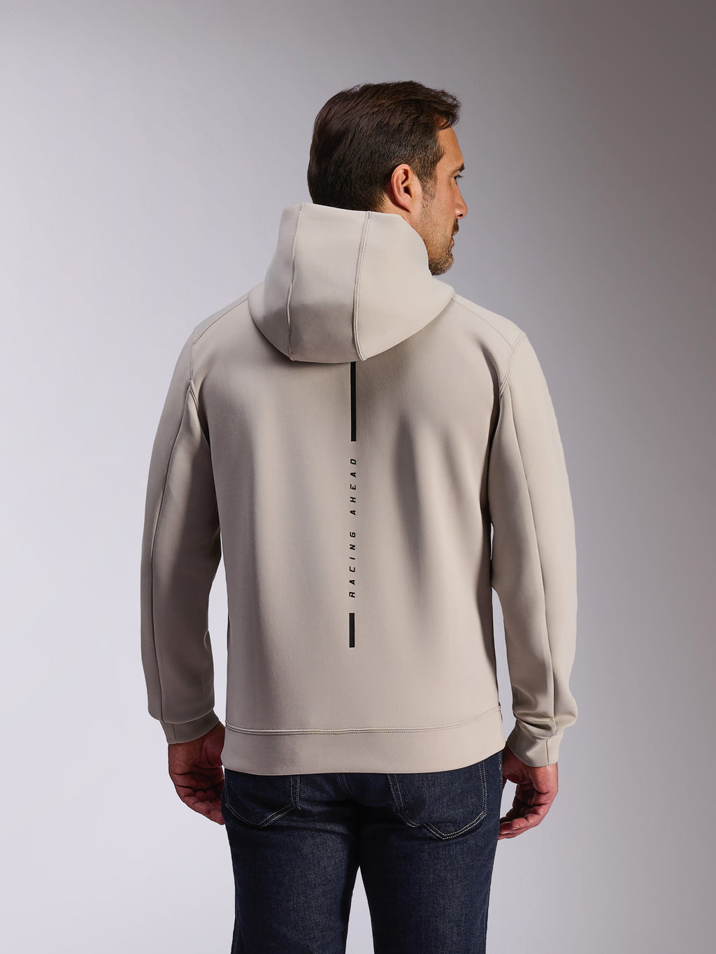 Alpinestars Felpa Insight Hoodie in Cement, vista posteriore di un modello che indossa una felpa pullover grigio chiaro, con logo a striscia verticale nera e scritta 'RACING AHEAD', felpa casual in pile double face ispirata al motorsport