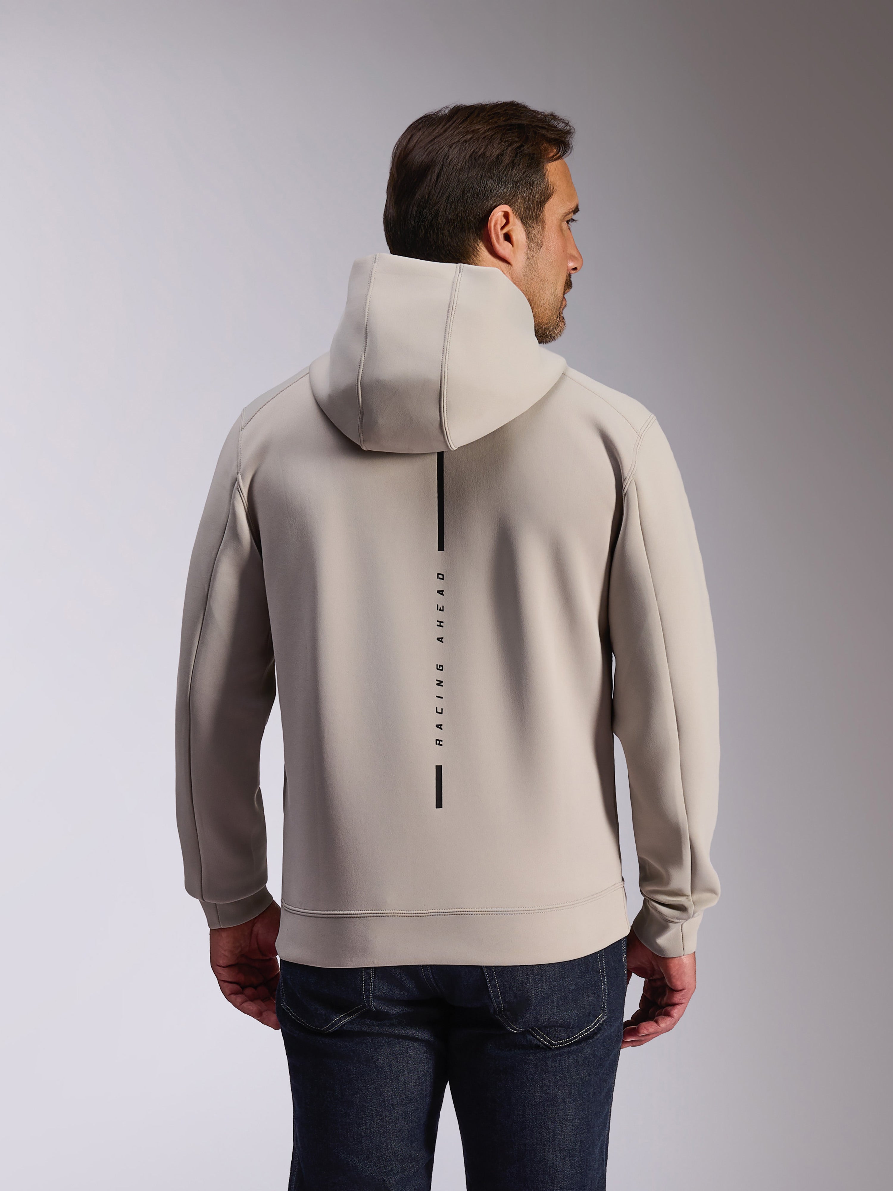 Alpinestars Felpa Insight Hoodie in Cement, vista posteriore di un modello che indossa una felpa pullover grigio chiaro, con logo a striscia verticale nera e scritta 'RACING AHEAD', felpa casual in pile double face ispirata al motorsport