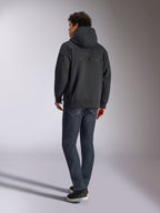 Felpa con cappuccio Alpinestars Emergent Oversized, nero, vista posteriore con logo Alpinestars in ricamo 3D sulle spalle, vestibilità oversize, abbinata a jeans in denim blu scuro e sneaker nere, streetwear casual ispirato al motorsport