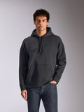 Alpinestars Emergent Oversized Hoodie, nero, modello che indossa una felpa con cappuccio oversize in pile, logo Astars ricamato in 3D tono su tono, tasca a marsupio, cappuccio con cordino, streetwear casual ispirato al motorsport