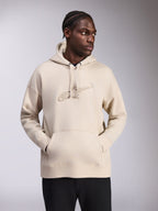 Felpa con cappuccio Alpinestars Emergent Oversized, colore sabbia, pullover vestibilità ampia con logo Astars ricamato in 3D tono su tono sul petto, tasca a marsupio, cappuccio con cordino, stile streetwear casual indossato da un modello con pantaloni neri