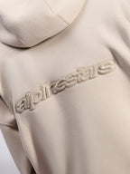 Felpa con cappuccio Alpinestars Emergent Oversized, streetwear casual, colore sabbia, vista dettagliata del logo Alpinestars con ricamo 3D tono su tono sul retro, texture in pile premium