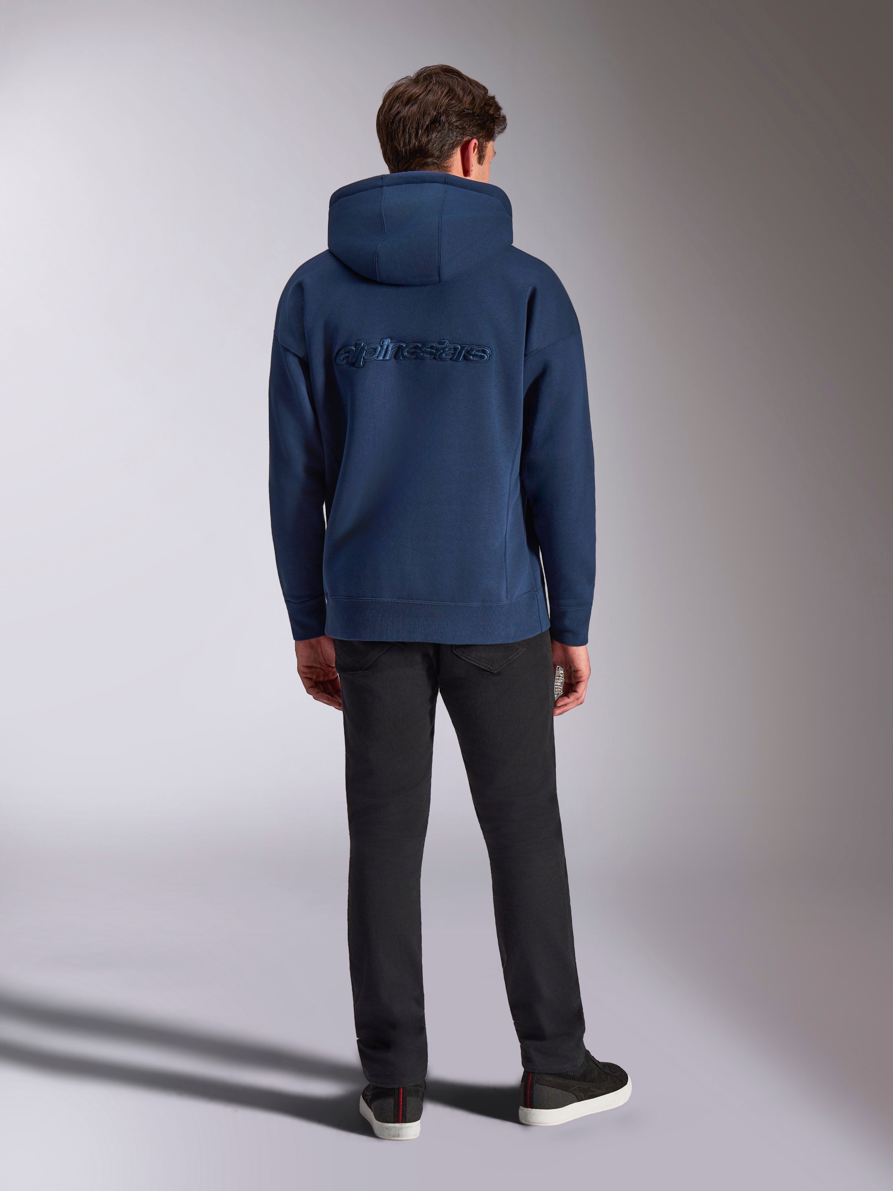 Alpinestars Emergent Oversized Hoodie, felpa streetwear casual, blu navy, scritta Alpinestars ricamata in tinta sul retro, vestibilità oversize con cappuccio, abbinata a pantaloni neri, vista posteriore
