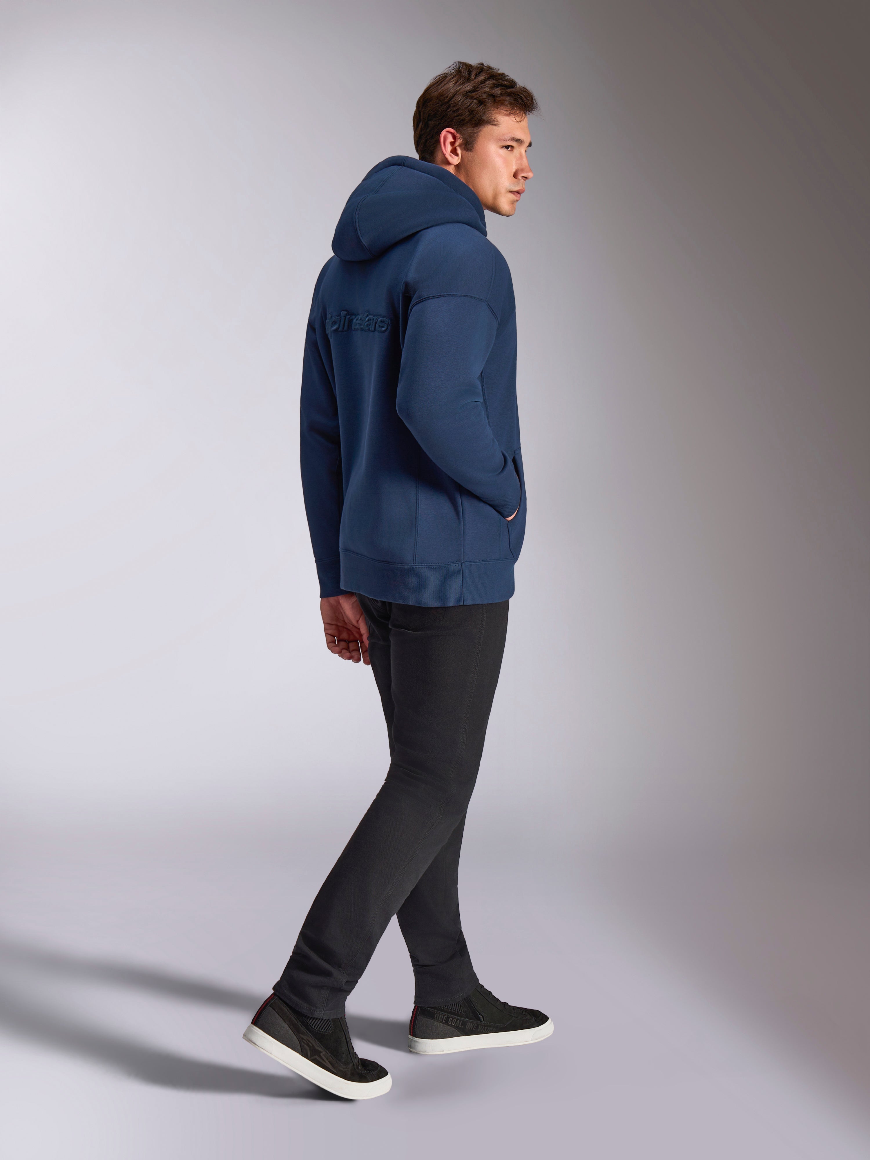 Felpa con cappuccio Alpinestars Emergent Oversized in blu navy, vista posteriore con logo Alpinestars ricamato in 3D, vestibilità oversize in pile con cappuccio e cordino, indossata con pantaloni neri, streetwear casual ispirato al motorsport