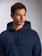 Felpa con cappuccio Alpinestars Emergent Oversized, blu navy, primo piano di un modello che indossa una felpa in pile, con logo Astars ricamato in 3D tono su tono sul petto, cappuccio con cordino regolabile, streetwear casual ispirato al motorsport