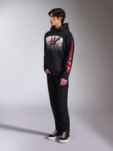 Alpinestars Obsessed Hoodie, felpa in pile nera, con una grande grafica bianca punteggiata sul petto, logo Astars rosso e branding rosso sulle maniche, indossata da un modello con pantaloni neri e sneaker, streetwear casual motorsport