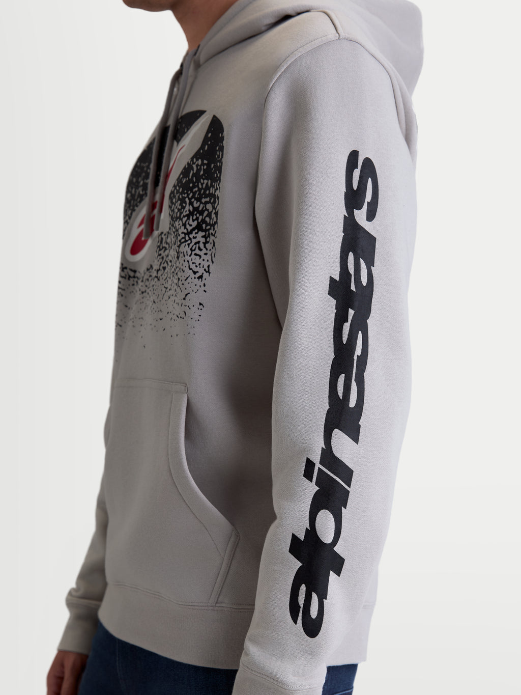 Alpinestars Felpa con cappuccio Obsessed, felpa casual motorsport unisex, grigio cemento e nero, vista laterale su modello con logo Alpinestars verticale sulla manica e grafica MX sfumata sul petto, in pile di cotone e poliestere riciclato.