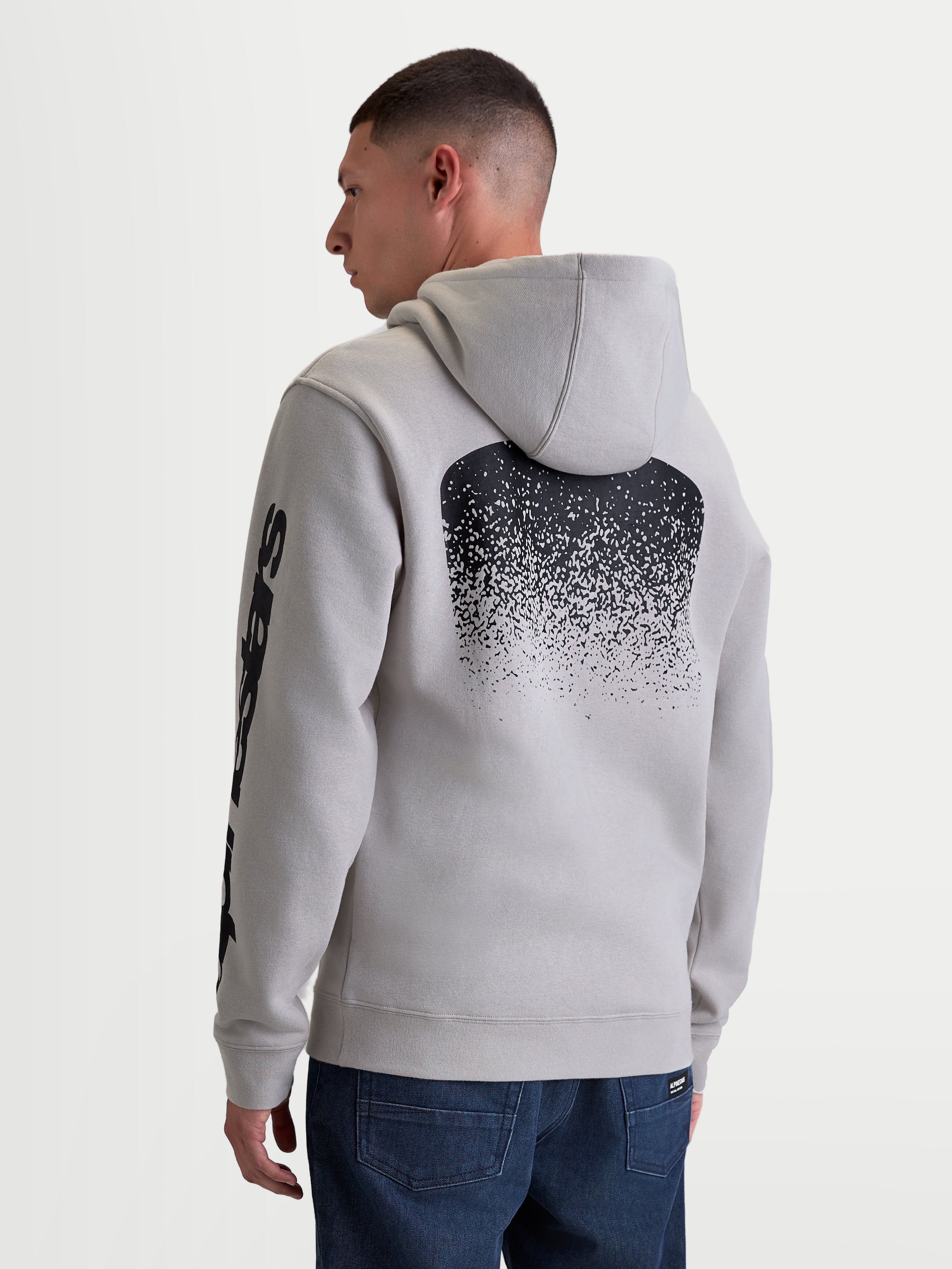 Alpinestars Felpa con cappuccio Obsessed, felpa in pile sportswear da uomo, grigio cemento, con grande grafica posteriore sfumata nera ispirata all'MX e logo sulla manica, vista posteriore su modello, abbigliamento casual motorsport.