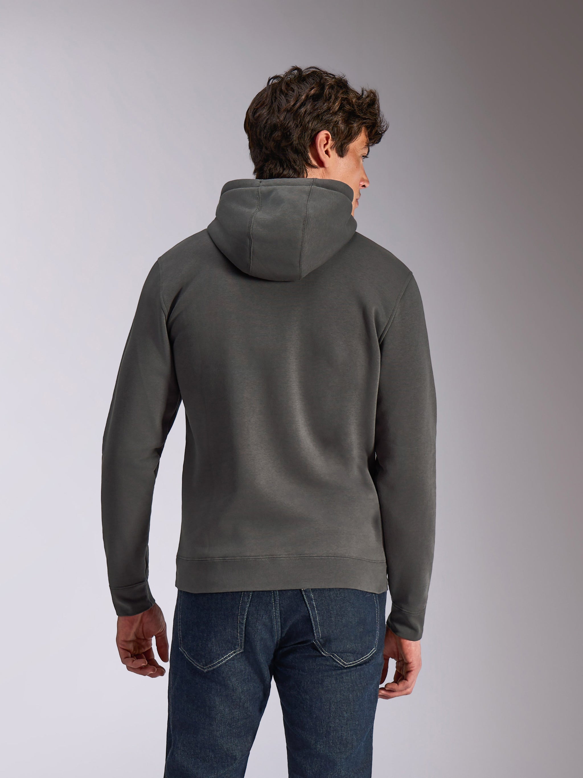 Alpinestars Ellipsoid Hoodie, felpa con cappuccio grigio gunmetal, abbigliamento sportivo casual, vista posteriore di un uomo che indossa una felpa in pile, orlo e polsini a coste, abbinata a jeans blu