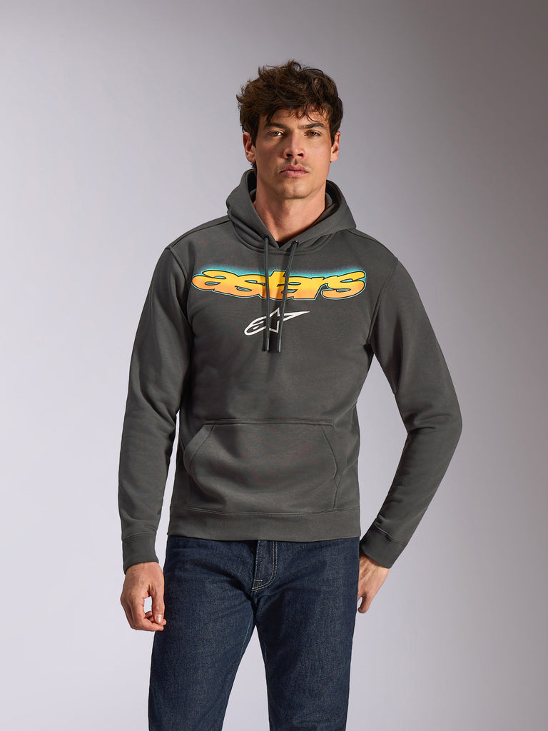 Felpa con cappuccio Alpinestars Ellipsoid, abbigliamento sportivo casual, grigio gunmetal con scritta Astars a gradiente giallo e blu e logo bianco, modello pullover con cappuccio e cordino, indossata con jeans blu scuro