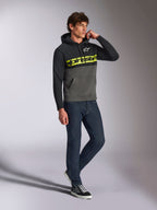 Felpa con cappuccio Alpinestars Parallel, streetwear casual, design a blocchi di colore nero e grigio gunmetal, logo word Alpinestars giallo neon sul petto, logo Astars bianco, cappuccio con cordino, indossata con jeans scuri e sneakers