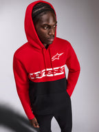 Felpa con cappuccio Alpinestars Parallel, felpa casual pullover, design a blocchi di colore rosso e nero, logo Alpinestars Word e logo Astars bianchi sul petto, indossata da un uomo con il cappuccio sollevato e pantaloni neri, streetwear ispirato al motorsport
