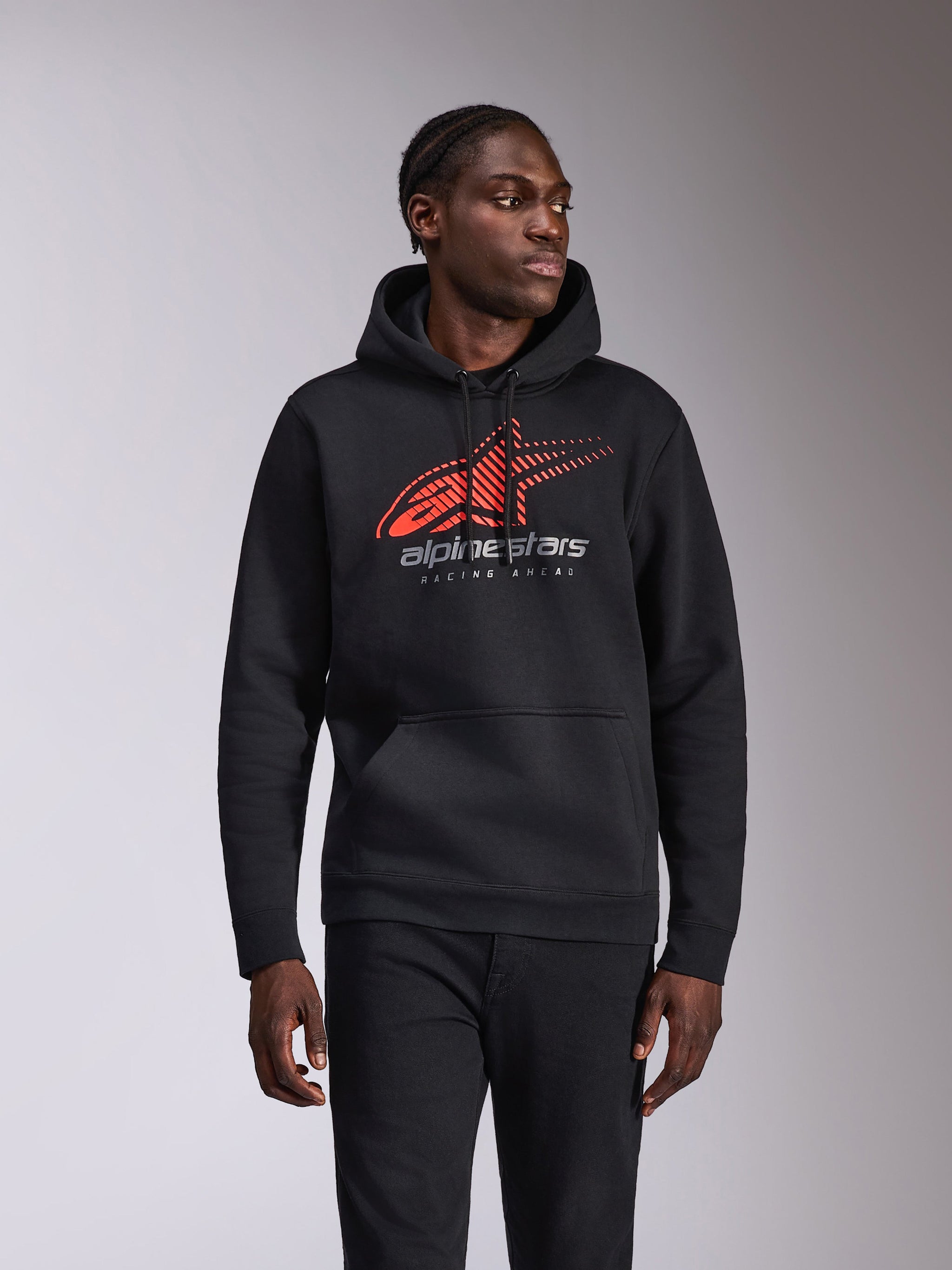 Alpinestars Pulse Hoodie, felpa casual con cappuccio, nera con logo Astars rosso e grigio caratterizzato da sfumatura speed line e testo 'Racing Ahead', cappuccio con cordino e tasca a marsupio, abbigliamento streetwear ispirato al motorsport indossata da un modello