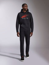 Alpinestars Pulse Hoodie, felpa con cappuccio casual streetwear nera, logo Astars combo rosso e grigio con linea di velocità sfumata sul petto, cappuccio con cordino, tasca a marsupio anteriore, maniche lunghe, abbinata a pantaloni neri e sneakers, design ispirato al motorsport