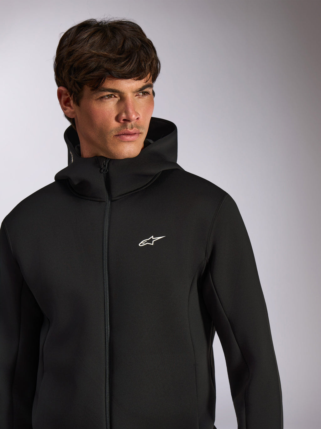 Alpinestars Cypher Hoodie, abbigliamento sportivo casual, felpa nera con zip frontale e cappuccio, logo Astars bianco sul petto, design del cappuccio a collo alto, indossata da un modello