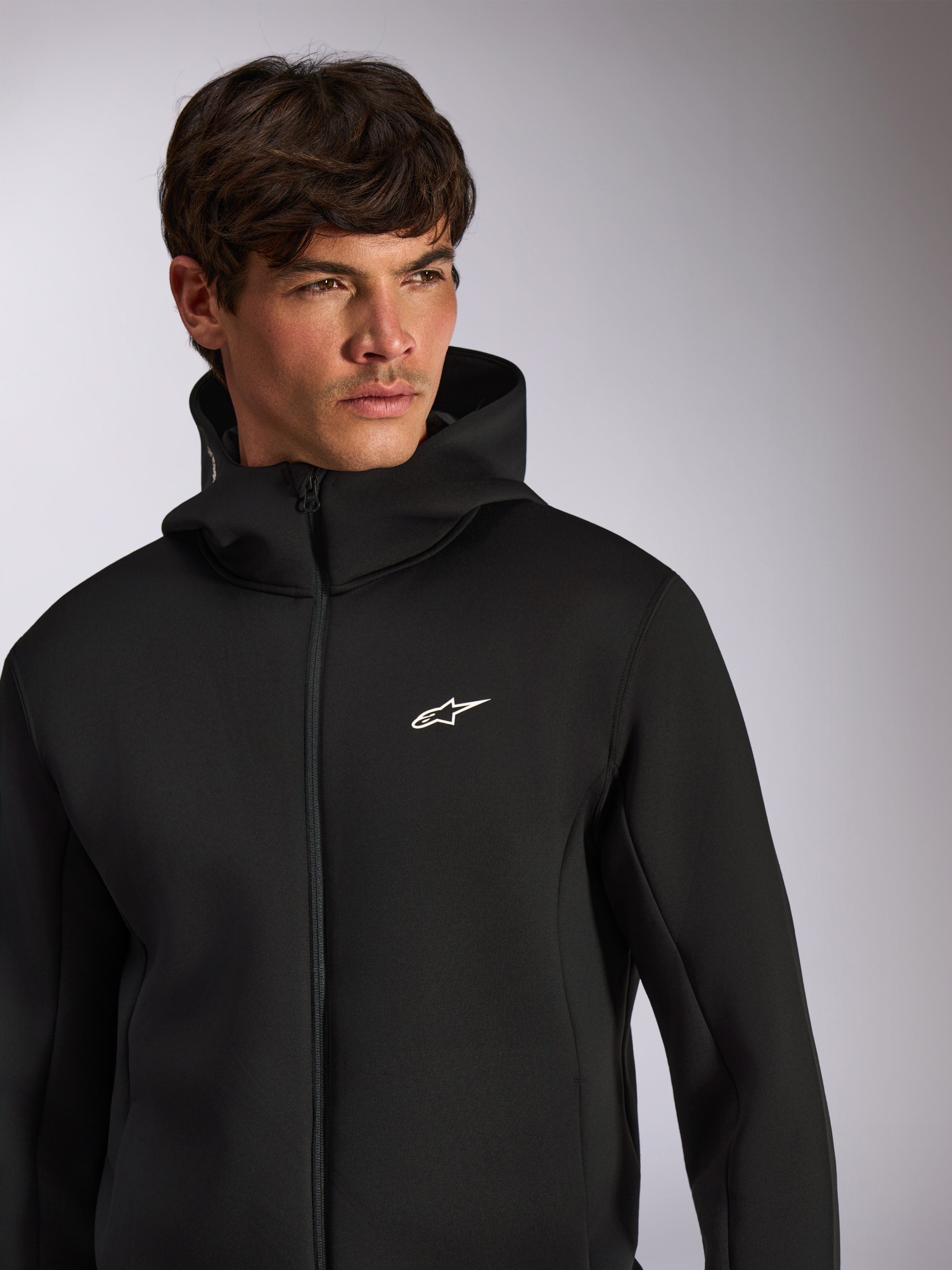 Alpinestars Cypher Hoodie, abbigliamento sportivo casual, felpa nera con zip frontale e cappuccio, logo Astars bianco sul petto, design del cappuccio a collo alto, indossata da un modello