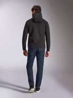 Alpinestars Cypher Hoodie, pile double-face nero, vista posteriore con piccolo logo Alpinestars bianco sul fianco sinistro, cappuccio a collo alto, abbinata a jeans blu scuro, streetwear casual ispirato al motorsport