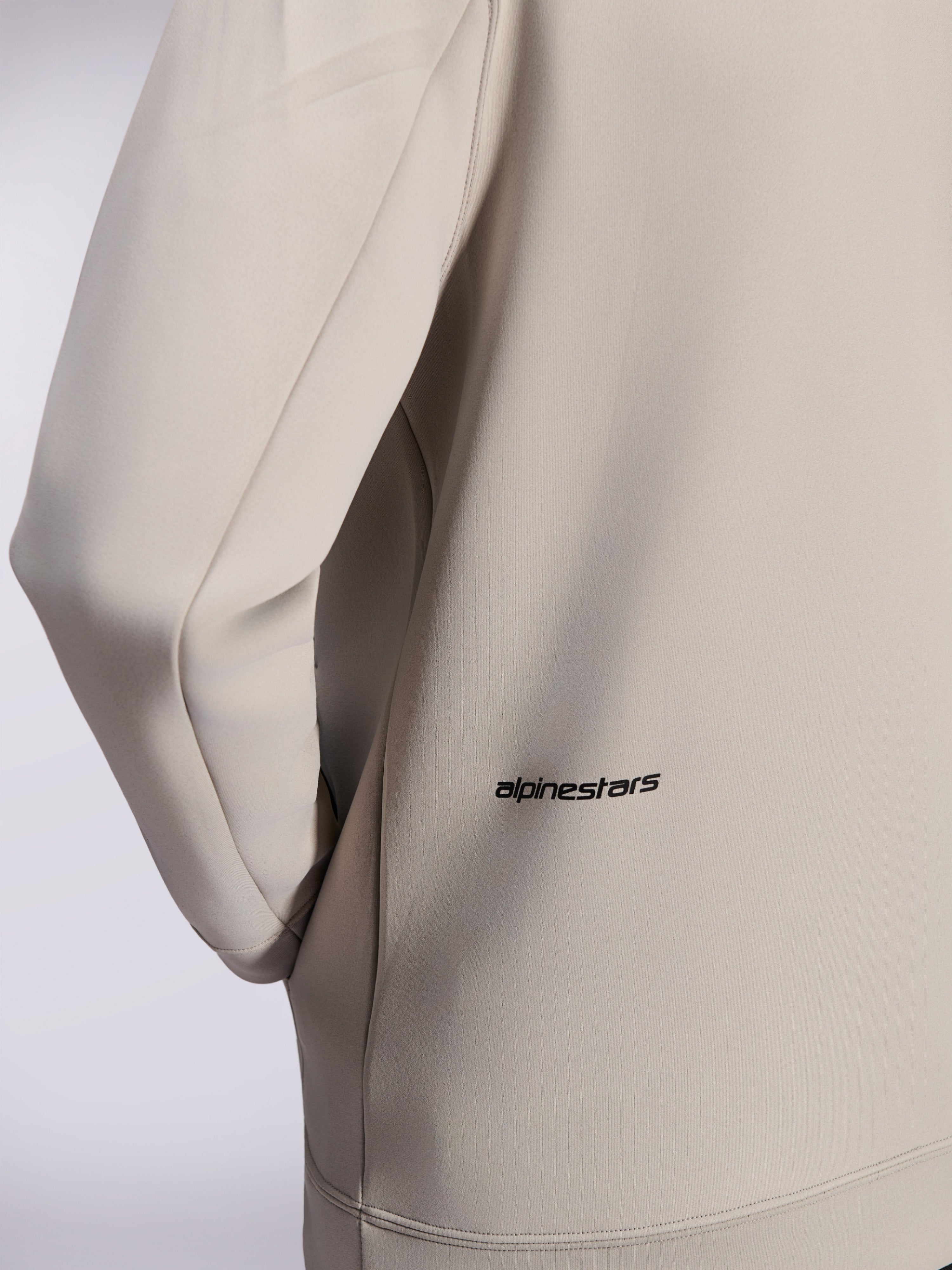 Alpinestars Cypher Hoodie, felpa con zip in pile double face, grigio Cement, primo piano del piccolo logo Alpinestars nero sulla parte bassa della schiena, dettaglio della tasca sulla cucitura e della trama liscia del tessuto