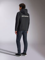 Felpa con cappuccio Alpinestars Transverse, felpa nera con zip frontale, vista posteriore con logo Alpinestars bianco sulle spalle, indossata con jeans blu scuro e sneakers nere, streetwear casual ispirato al motorsport