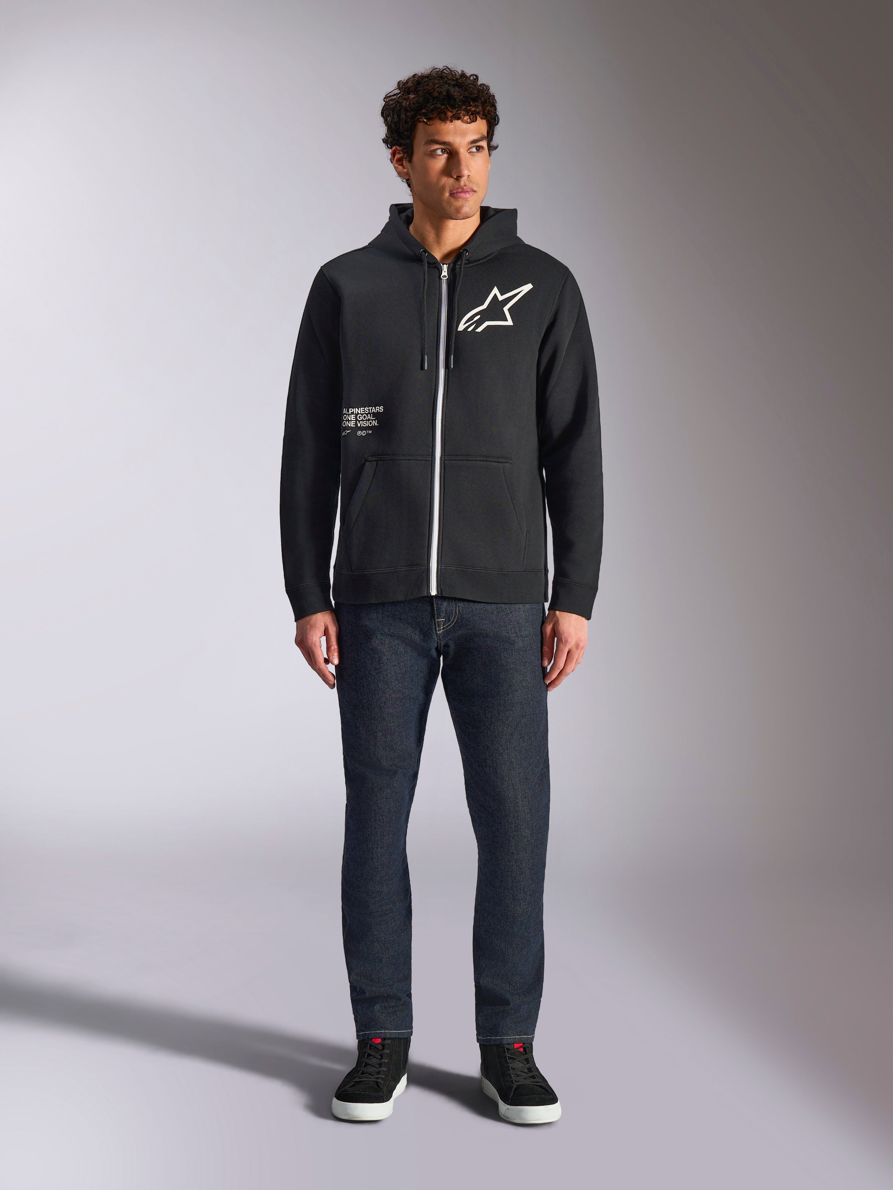 Alpinestars Felpa con cappuccio Transverse, felpa casual con zip frontale, nera, logo Astars bianco sul petto e stampa 'One Goal' sul davanti, cappuccio con coulisse, abbinata a jeans scuri e sneakers nere, streetwear lifestyle motorsport
