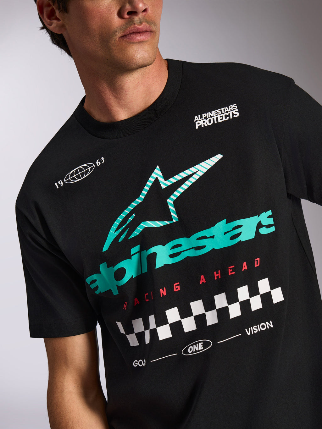 Alpinestars Aplomb Oversized CSF Tee, maglietta a maniche corte, nero, logo Astars a strisce verde acqua e bianco, scritta 'Racing Ahead' rossa con motivo a bandiera a scacchi, streetwear casual motorsport