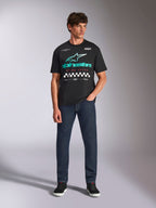 Alpinestars Aplomb Oversized CSF Tee, t-shirt a maniche corte, nero, logo Astars con sfumatura verde acqua, scritta 'Racing Ahead' rossa e dettagli a scacchi, indossata da un modello con jeans blu scuro, streetwear casual ispirato al motorsport