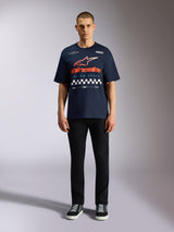 T-shirt Alpinestars Aplomb Oversized CSF, maglietta a maniche corte blu navy, grande grafica sul petto con logo a gradiente arancione e rosso e motivo a scacchi, indossata da un modello con pantaloni neri e sneakers, casual motorsport streetwear