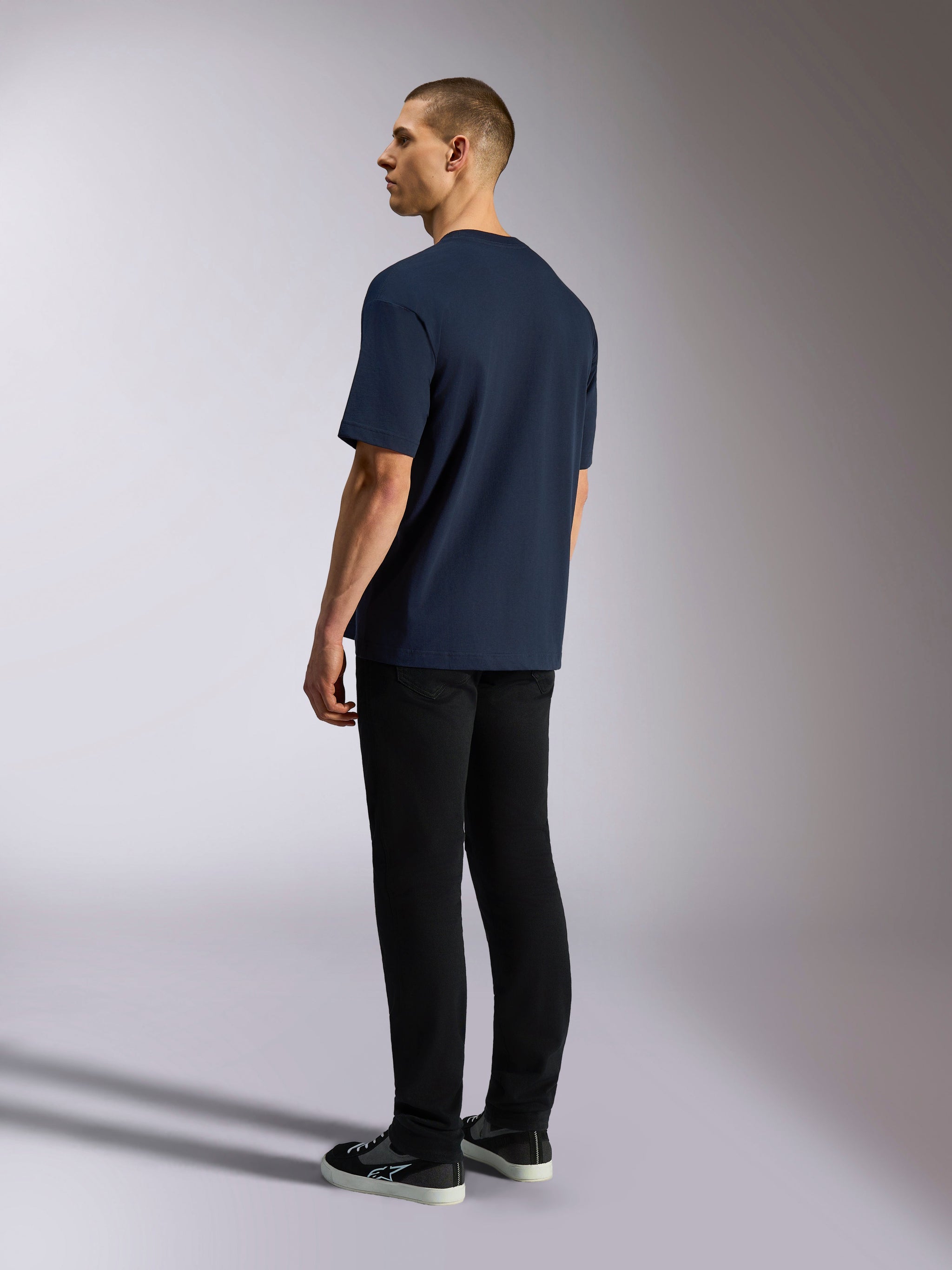 Alpinestars Aplomb Oversized CSF Tee, maglietta a maniche corte, blu navy, vista posteriore su modello, indossata con pantaloni neri e sneakers, streetwear casual ispirato al motorsport