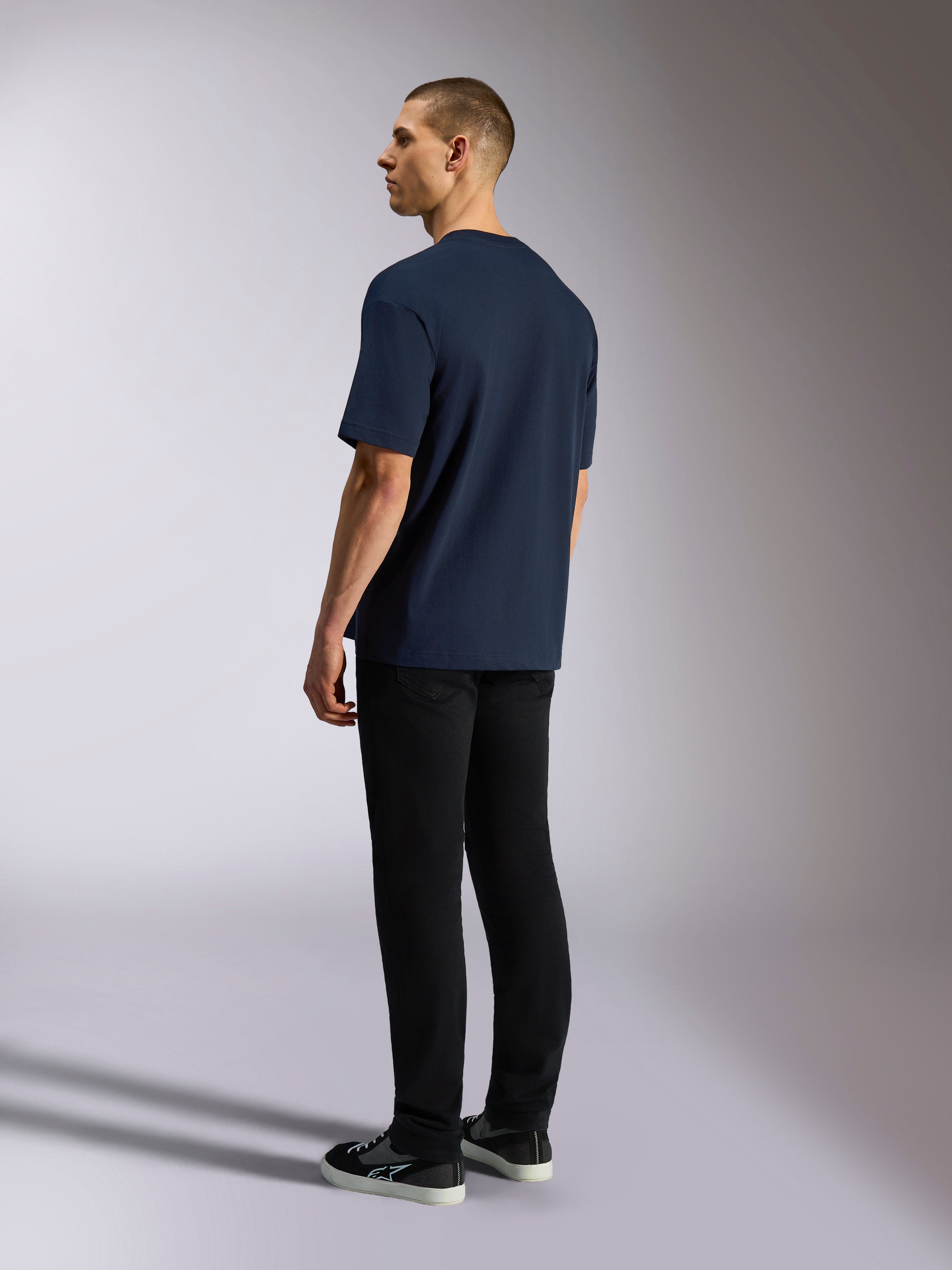 Alpinestars Aplomb Oversized CSF Tee, maglietta a maniche corte, blu navy, vista posteriore su modello, indossata con pantaloni neri e sneakers, streetwear casual ispirato al motorsport