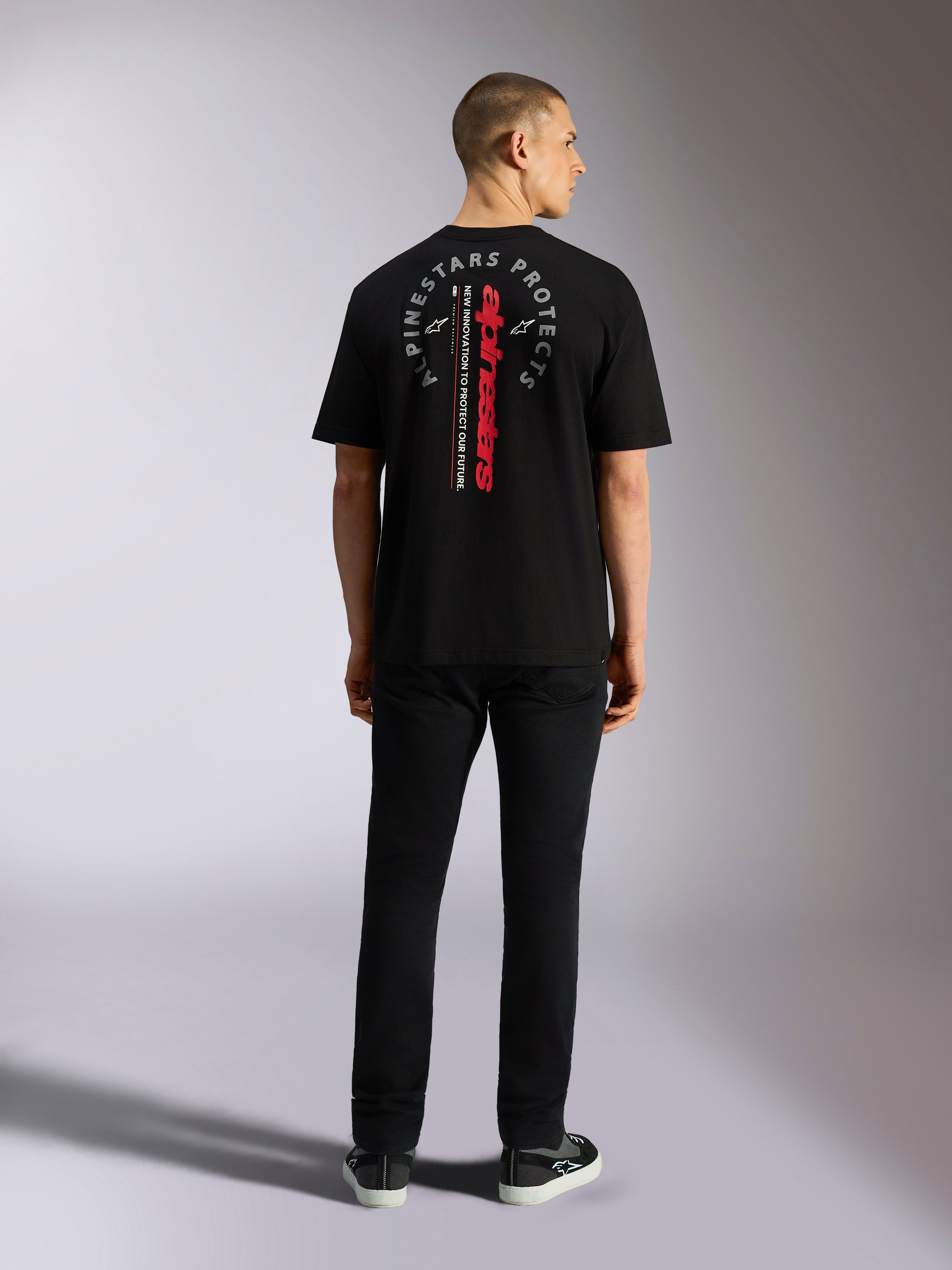 Alpinestars Overhang Oversized CSF Tee, t-shirt a maniche corte, nero, con marchio Alpinestars verticale rosso e grafica circolare grigia sul retro, indossata da un modello vista da dietro, streetwear casual motorsport