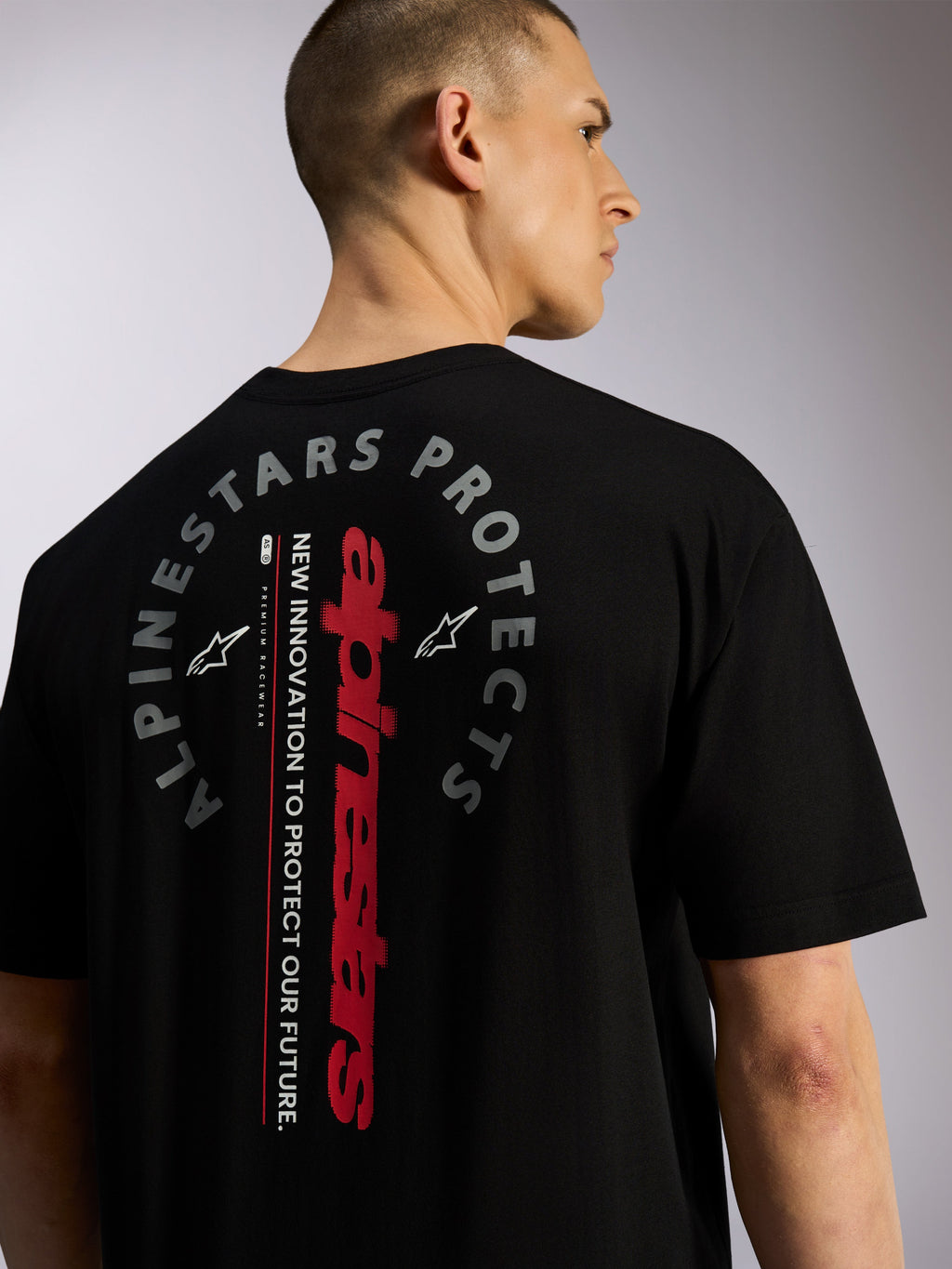 Maglietta Alpinestars Overhang Oversized CSF, t-shirt a maniche corte, nera, vista posteriore con logo Alpinestars verticale rosso e grafica circolare 'Alpinestars Protects', streetwear casual ispirato al motorsport