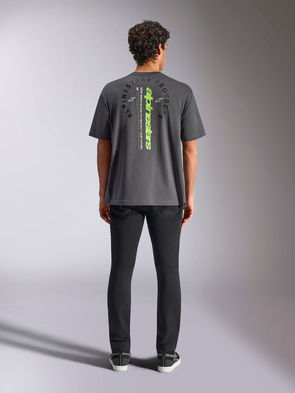 Alpinestars Overhang Oversized CSF Tee, t-shirt a maniche corte, grigio antracite, vista posteriore con logo Alpinestars verticale verde neon e testo grafico, vestibilità oversize, streetwear casual motorsport
